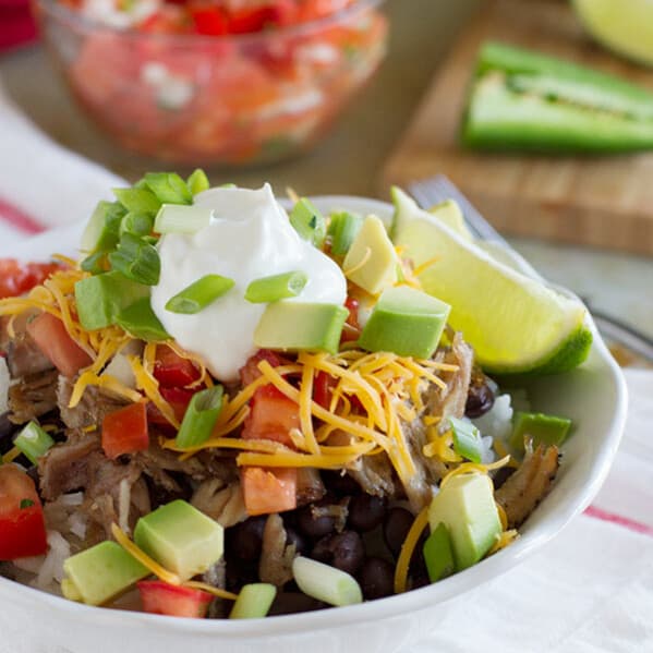 Caramelized pork carnitas are served over beans and rice, and topped with a fresh pico de gallo to make a burrito bowl that will rival the local take out joint!