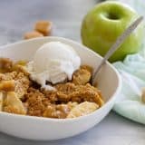 Caramel Apple Crisp in a bowl topped with ice cream.