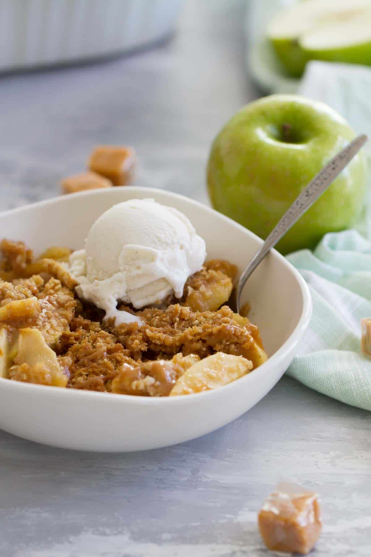 Caramel Apple Crisp in a bowl topped with vanilla ice cream.