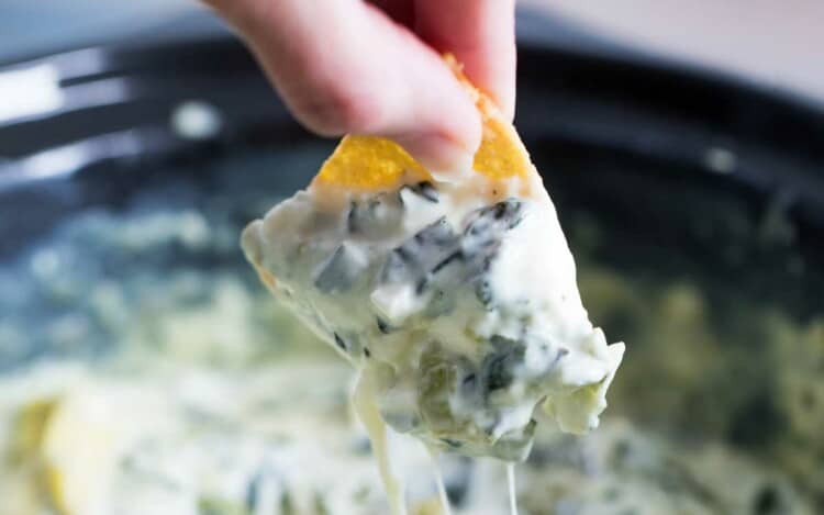 Crockpot Spinach Artichoke Dip with a chip dipping in