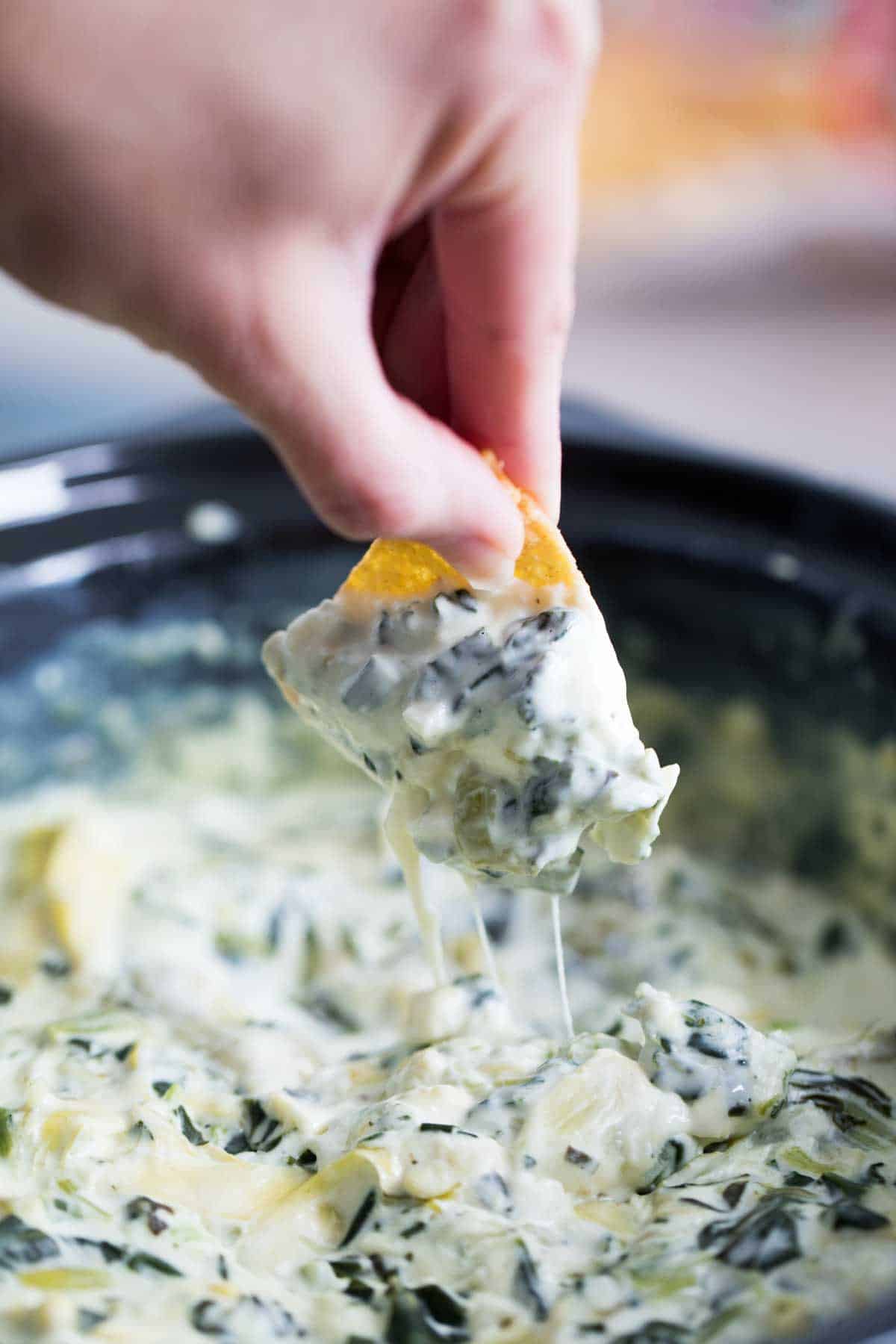 Crockpot Spinach Artichoke Dip with a chip dipping in