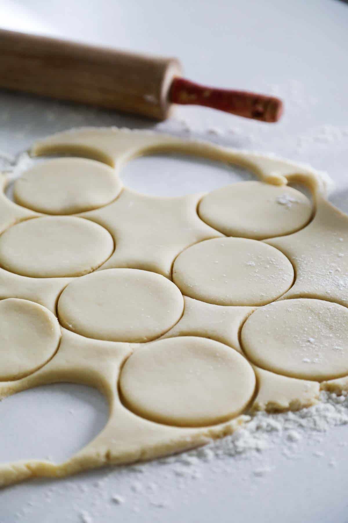 peppermint soft sugar cookie dough rolled out and circles being cut from it.