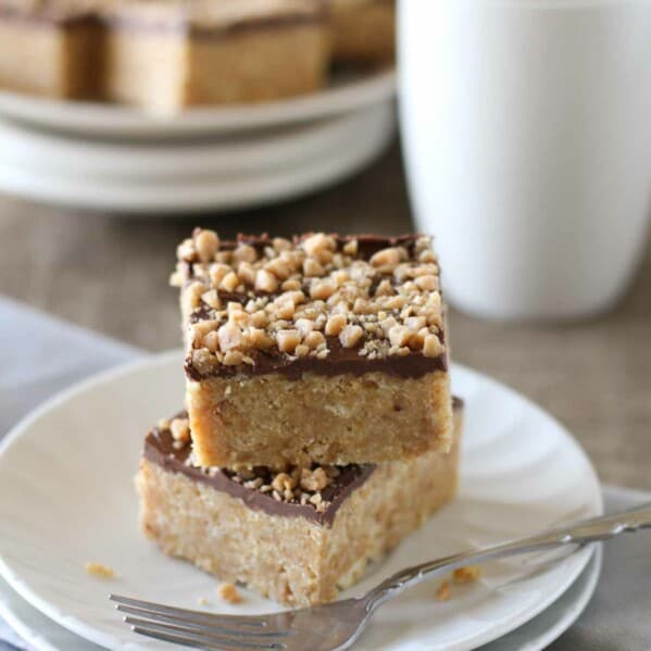 4 ingredient Skor Squares stacked on a plate with more behind.