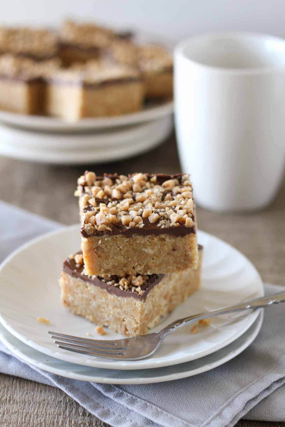 4 ingredient Skor Squares stacked on a plate with more behind.