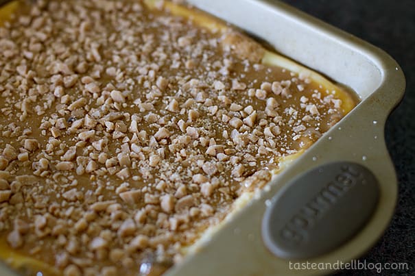 Adding toffee pieces to the top of caramel cookie cheesecake bars.