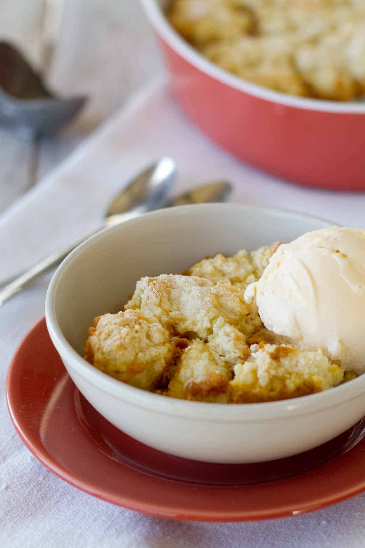 Bowl of pumpkin cobbler topped with vanilla ice cream.