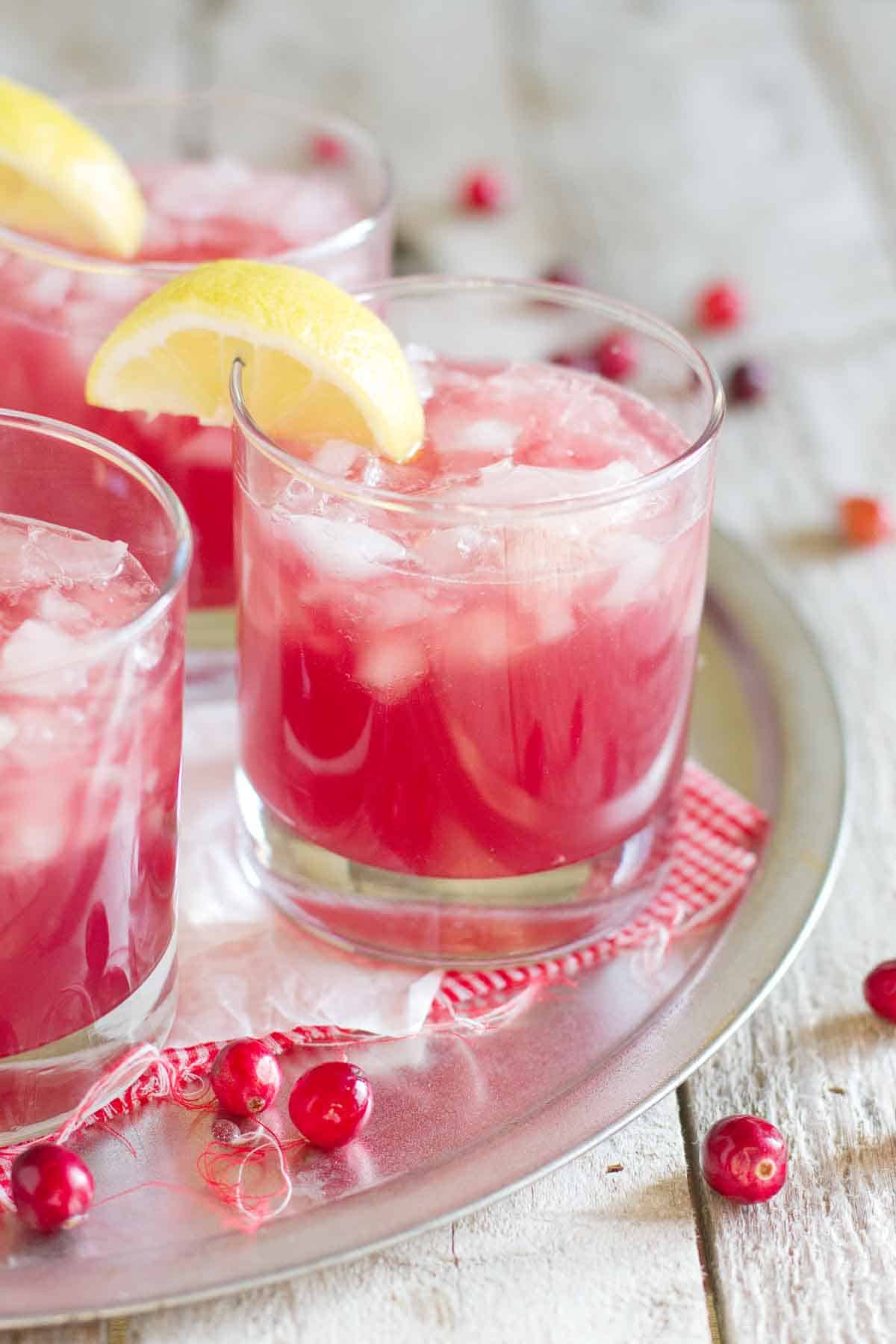 The perfect holiday drink, this Sparkling Cranberry Punch is family friendly and only takes minutes to prepare! glasses of sparkling cranberry punch with lemon slices on the glass