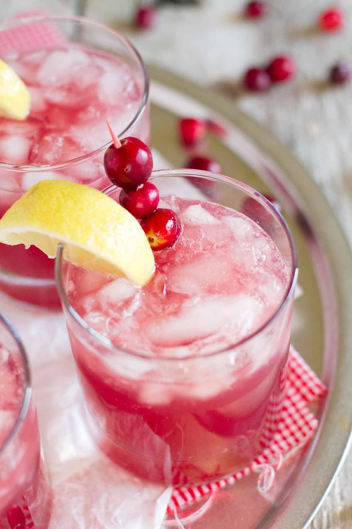 The perfect holiday drink, this Sparkling Cranberry Punch is family friendly and only takes minutes to prepare! Sparkling Cranberry Punch in a glass with a lemon slice and fresh cranberries