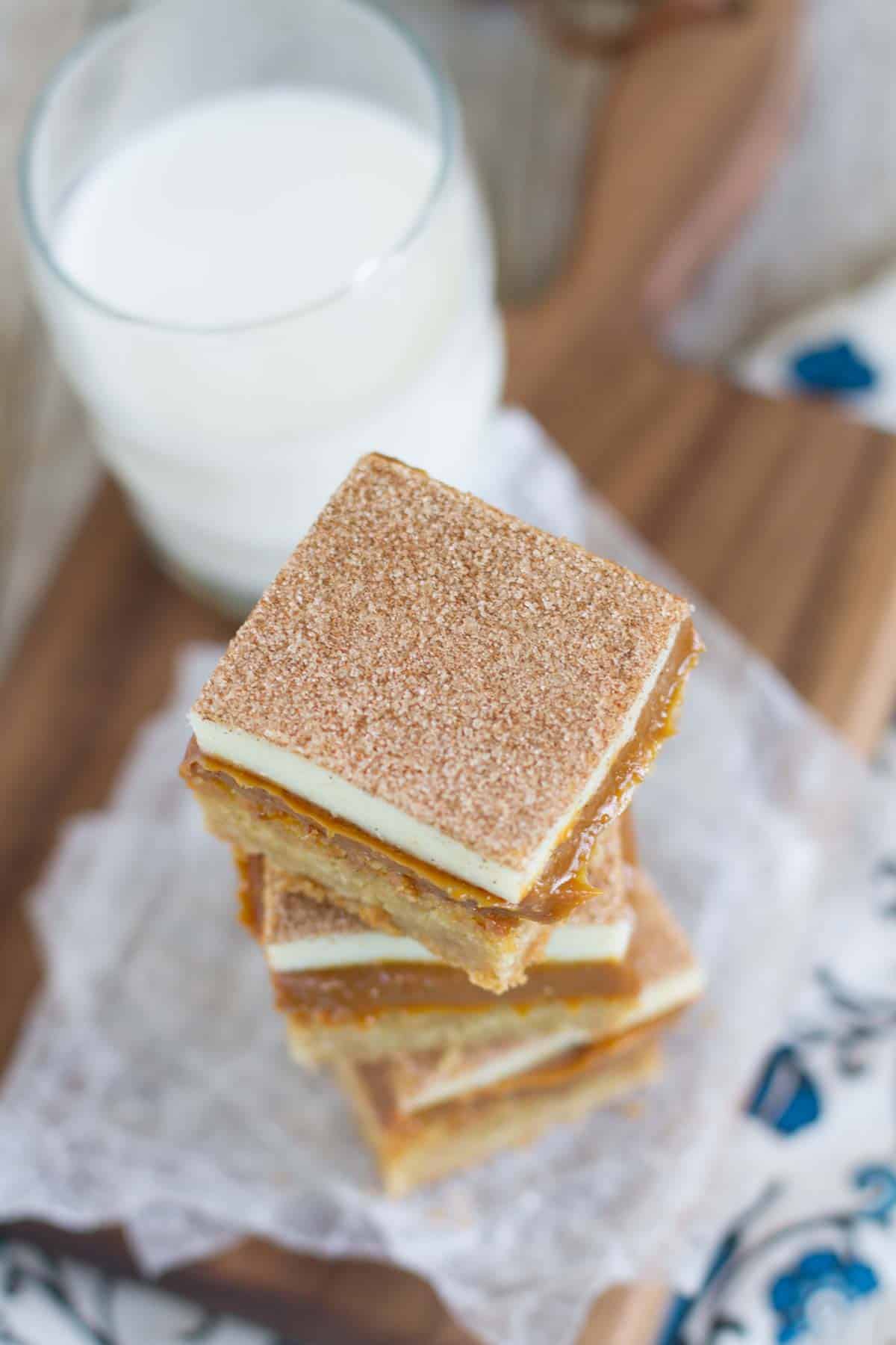 A soft, brown sugar blondie is topped with lots of dulce de leche, white chocolate, and of course, plenty of cinnamon-sugar in these Caramel Snickerdoodle Bars! Caramel Snickerdoodle Bars stacked on top of each other.