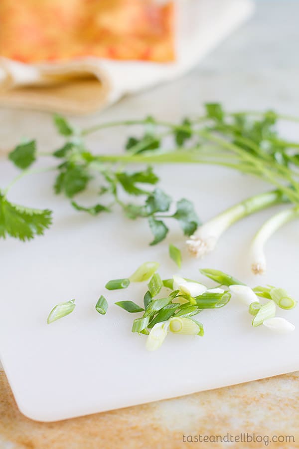 green onions and cilantro on a cutting board.