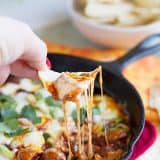 Chip dipping into chorizo mushroom queso dip.