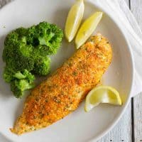 overhead view of tilapia on a plate with lemon slices and broccoli