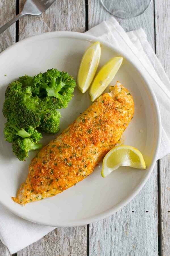 overhead view of tilapia on a plate with lemon slices and broccoli