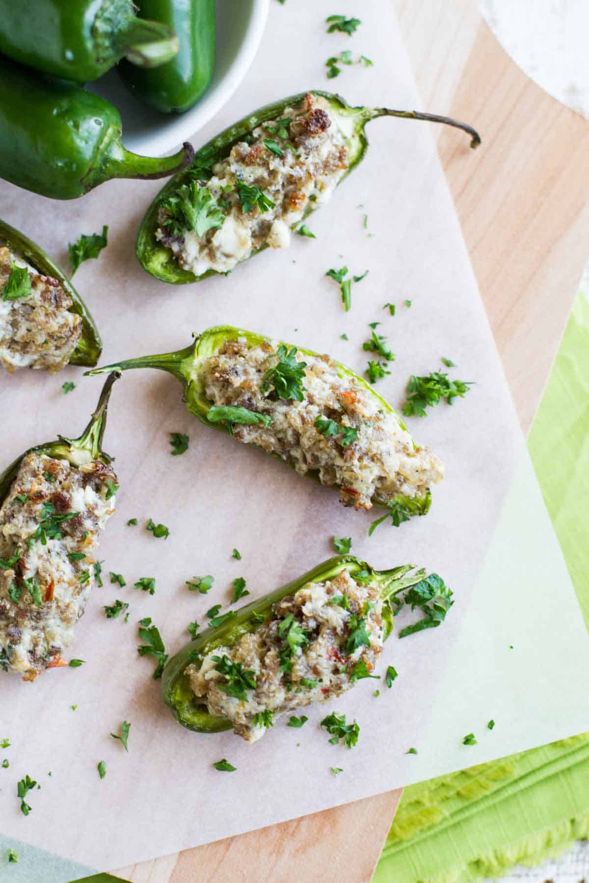 Sausage stuffed jalapeños on parchment paper.