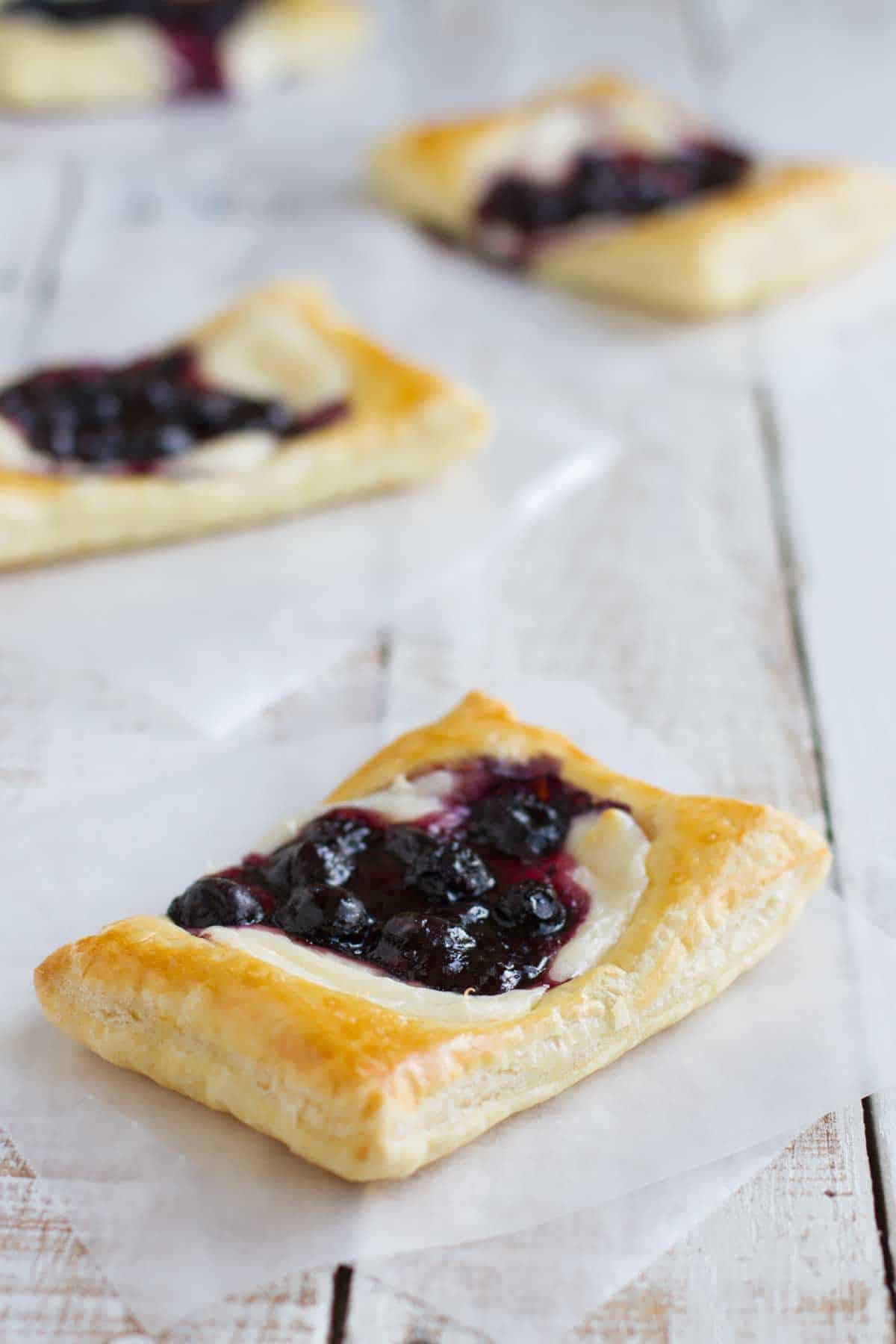 This Puff Pastry Danish with Blueberries and Cream Cheese starts with puff pastry that is topped with sweetened cream cheese and a blueberry mixture for a perfectly decadent breakfast treat. puff pastry rectangles topped with blueberries and cream cheese.