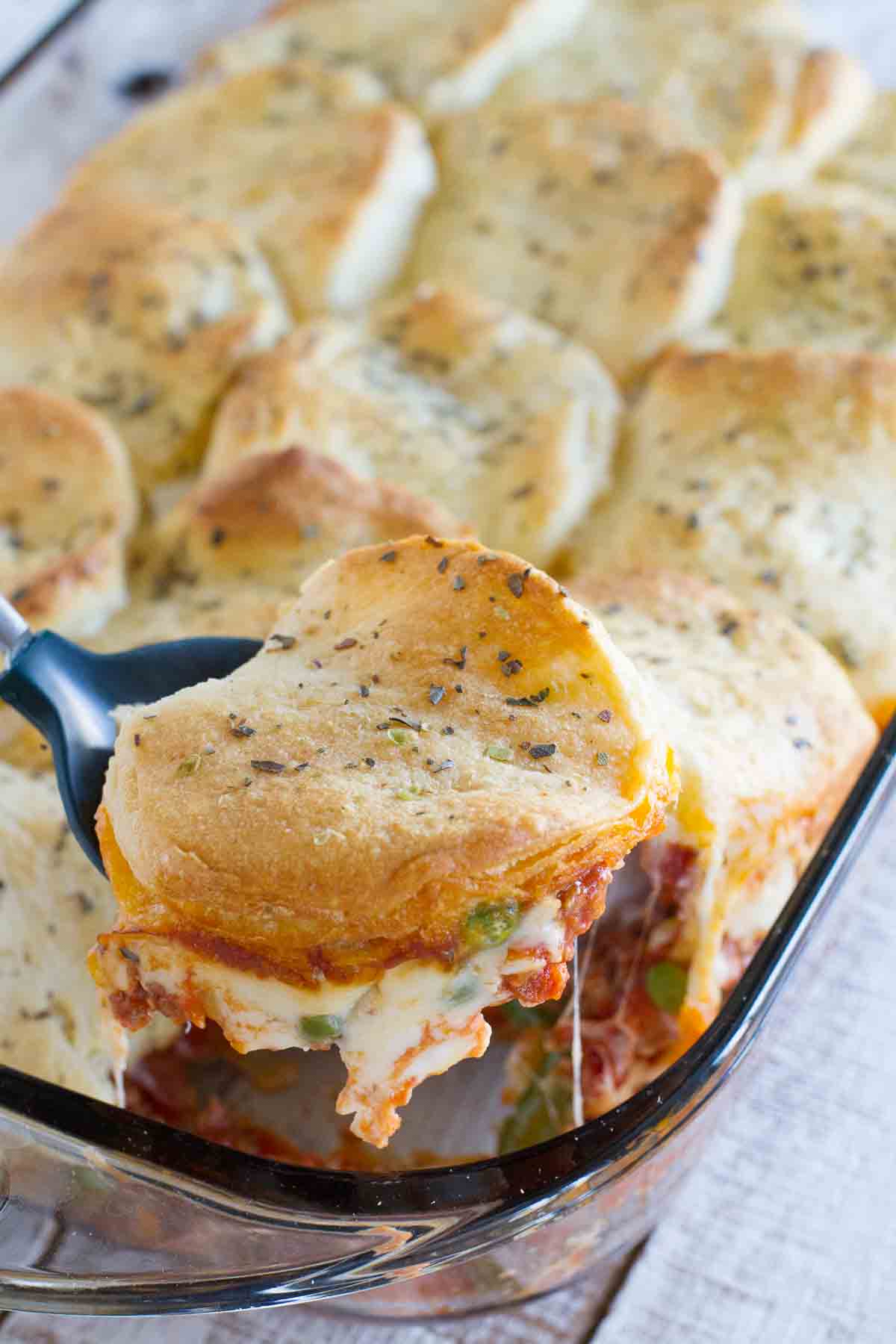 removing a serving of Italian Ground Beef Casserole with Biscuit Topping from a baking dish