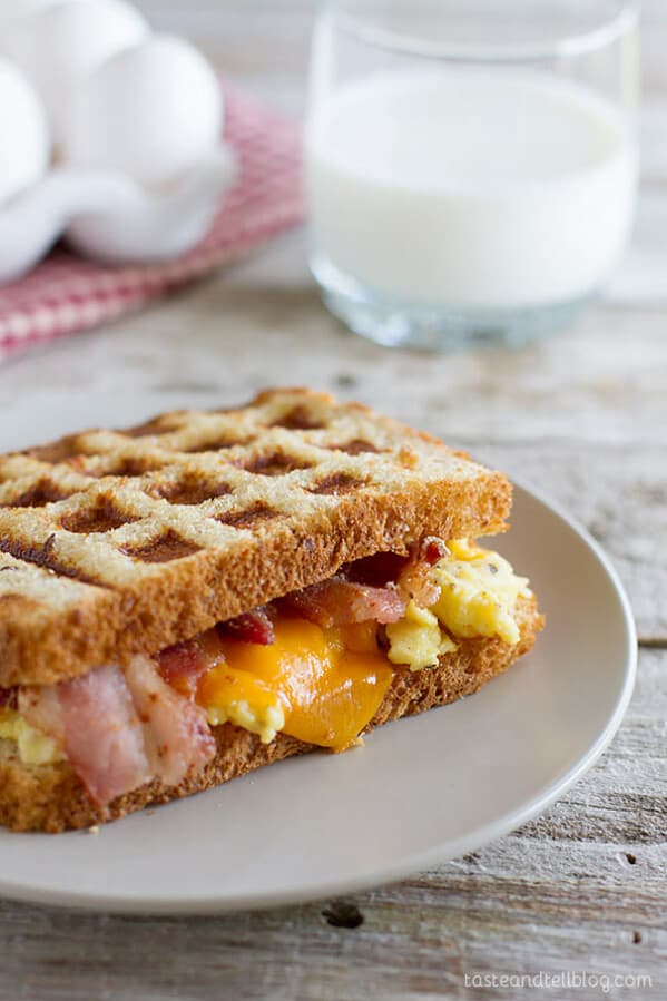 Waffled Breakfast Grilled Cheese Sandwich Recipe - Grilled cheese breakfast style! A breakfast grilled cheese sandwich recipe has scrambled eggs, bacon and cheese on toast that is cooked in a waffle maker for a fun breakfast idea.