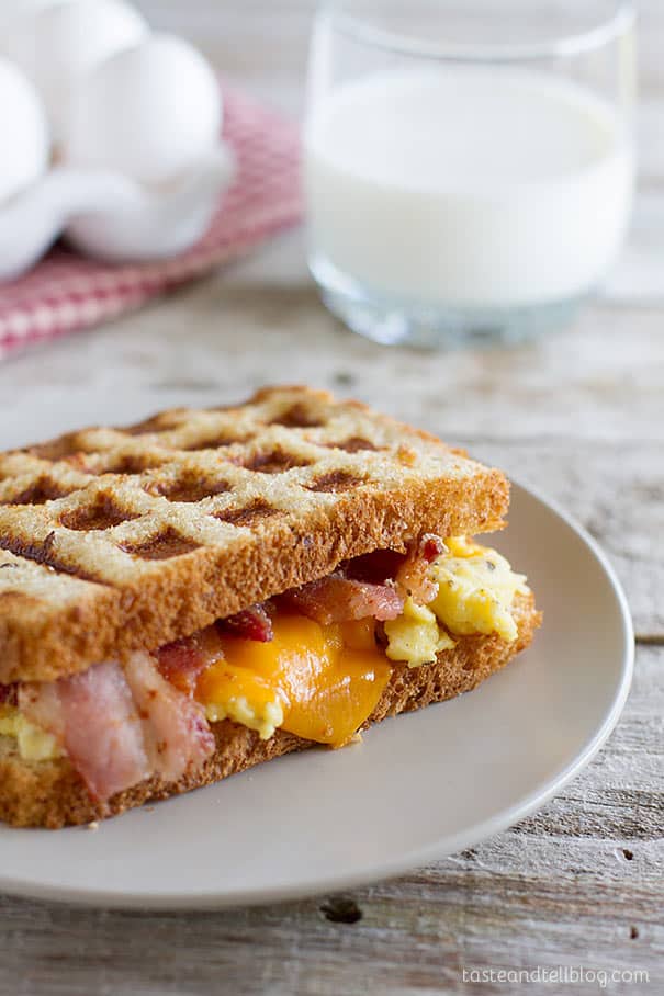 Waffled Breakfast Grilled Cheese Sandwich Recipe - Grilled cheese breakfast style! A breakfast grilled cheese sandwich recipe has scrambled eggs, bacon and cheese on toast that is cooked in a waffle maker for a fun breakfast idea.