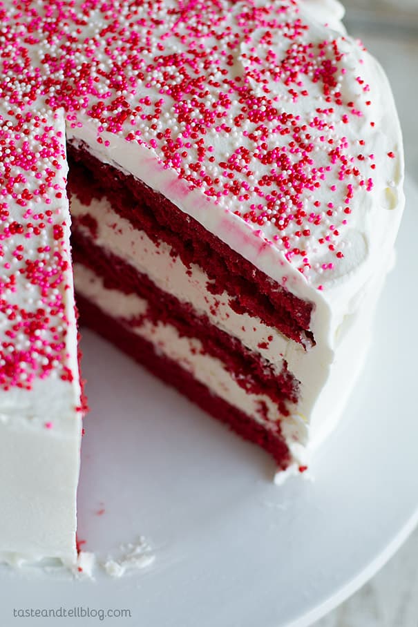 Red Velvet Ice Cream Cake topped with sprinkles and with a slice removed.