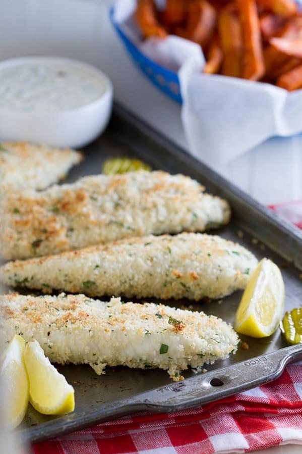 Panko crusted tilapia on a baking sheet with lemons.