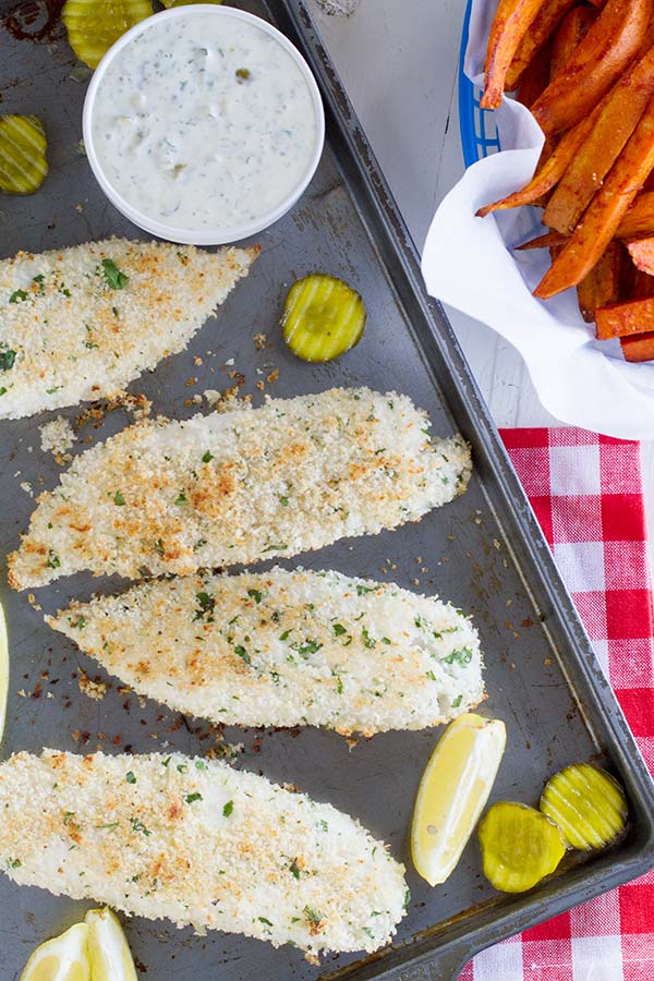 Pieces of panko crusted fish with homemade sauce and lemon slices.