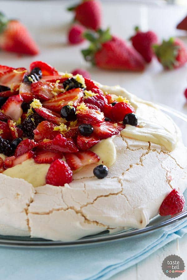 A light and delicate meringue cake is topped with whipped cream, silky creme anglaise and lots of berries in this Pavlova Recipe with Fresh Berries.