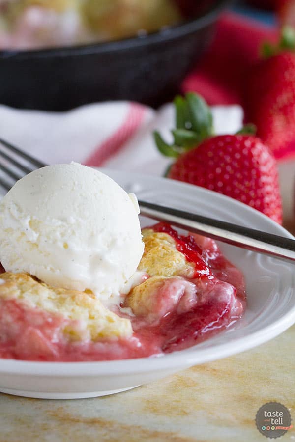 Bowl filled with strawberry cobbler topped with vanilla ice cream.