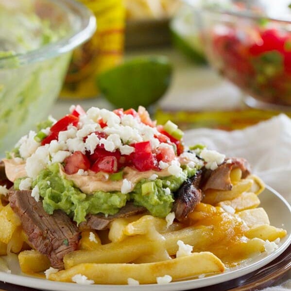 Truly indulgent, these Enchilada Steak Fries are an adaptation of the popular San Diego treat - Carne Asada Fries. French fries get topped with steak, guacamole, sour cream and pico de gallo for the perfect southern California dish.