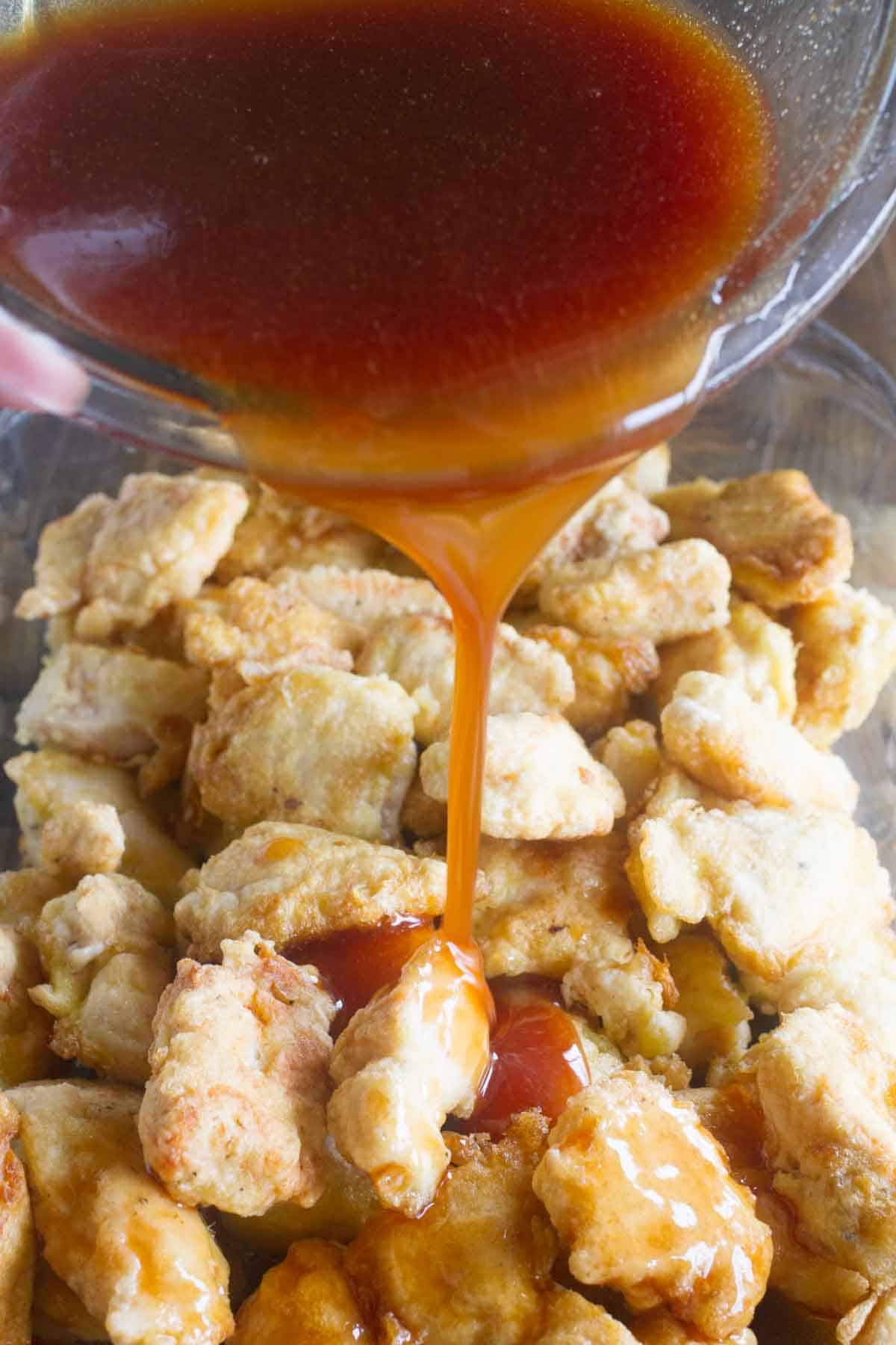 Pouring sweet and sour sauce over chicken.