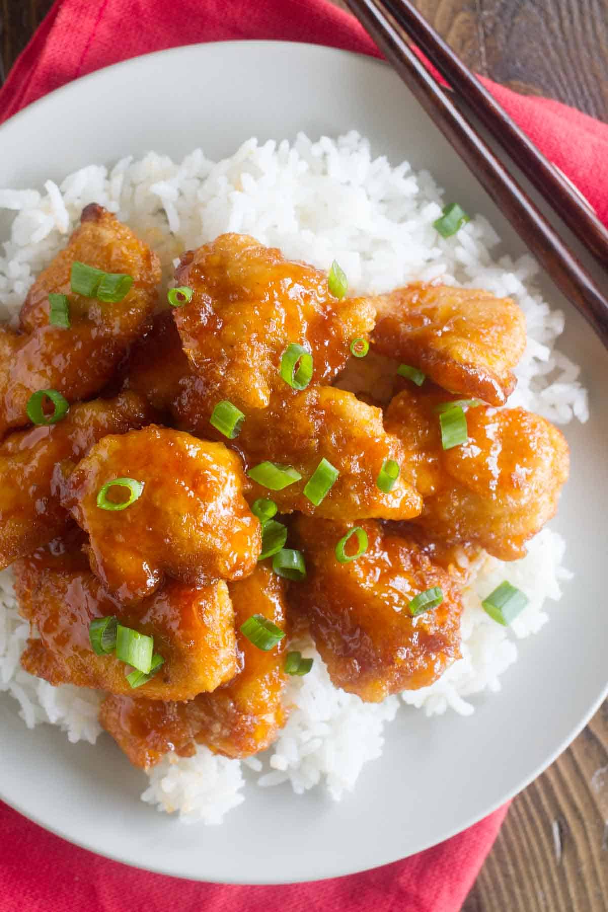 Sweet and sour chicken over rice with green onions.