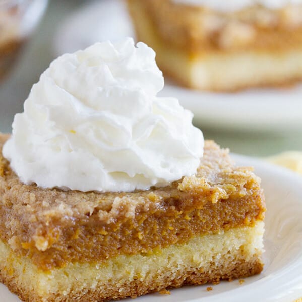 Slice of pumpkin pie cake topped with whipped cream.