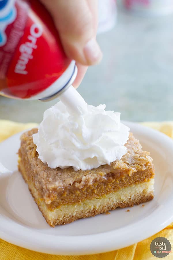 Putting whipped topping on pumpkin pie cake.