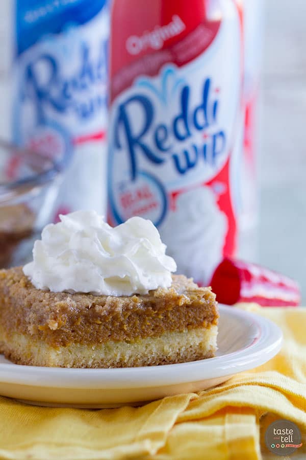 Slice of pumpkin pie cake with bottles of whipped topping behind.