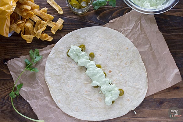 Adding avocado creama to a tortilla.