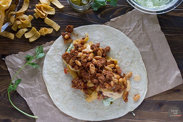 Adding chili to the top of ingredients to make a Frito pie burrito.