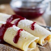 These Monte Cristo Crepes are sweet and savory and perfect for breakfast, brunch or dinner! Tender crepes are filled with cheese, ham and turkey and topped with raspberry jam and powdered sugar.