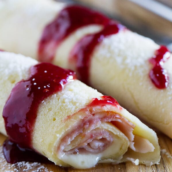 These Monte Cristo Crepes are sweet and savory and perfect for breakfast, brunch or dinner! Tender crepes are filled with cheese, ham and turkey and topped with raspberry jam and powdered sugar.