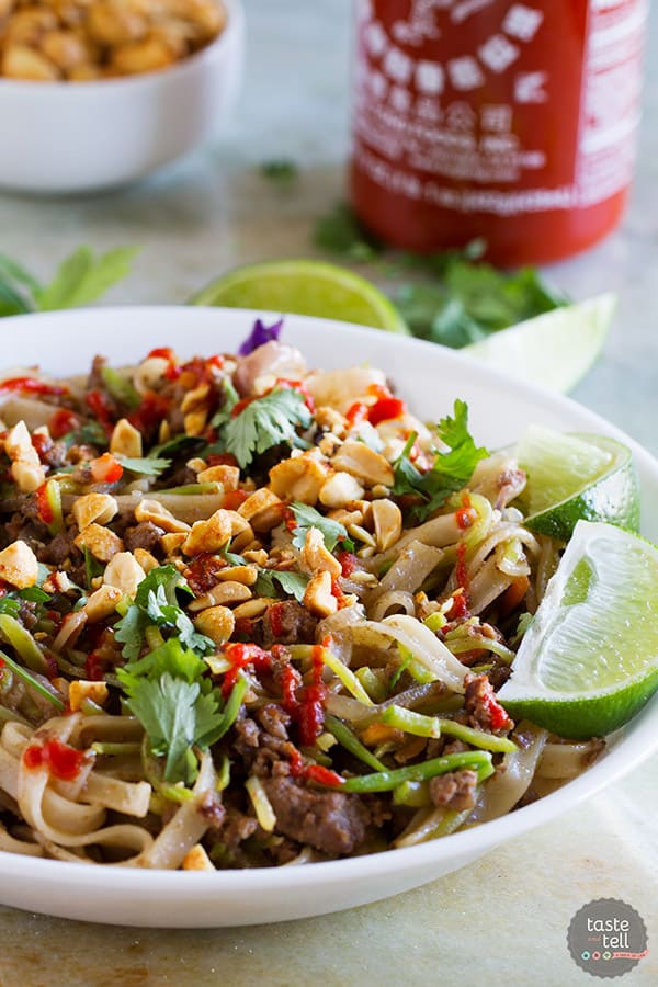 bowl with beef satay noodles topped with peanuts and sriracha.