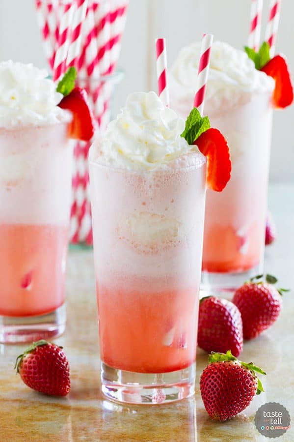 Three strawberry cream floats with fresh strawberries on the side.