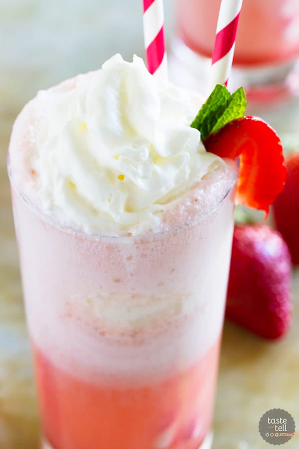 Strawberry cream float with a strawberry on the side and two straws.