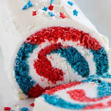 red white and blue cake roll with star sprinkles cut showing interior