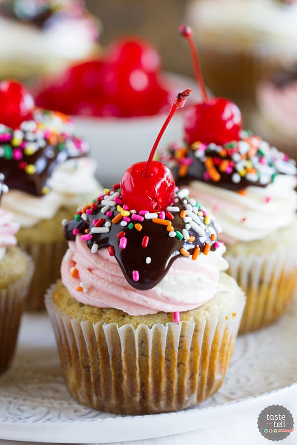 Banana splits - minus the ice cream! These Banana Split Cupcakes have tender, fluffy banana cupcakes topped with vanilla and strawberry frosting. Top it off with chocolate ganache, sprinkles and a cherry for the cupcake version of a banana split!