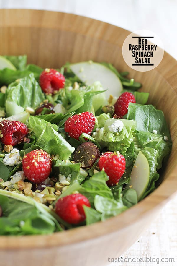 This Red Raspberry Spinach Salad is a salad with spinach, romaine, grapes, dried cranberries, pear, raspberries, blue cheese and pistachios that is served with a raspberry vinaigrette.