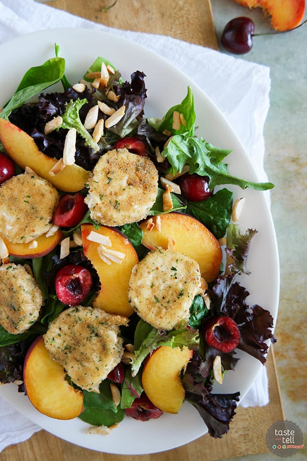 Salad topped with peaches and cherries and fried goat cheese.