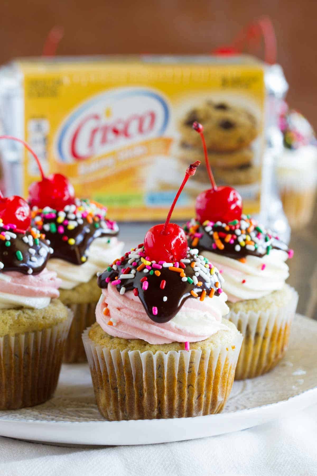 Banana cupcakes topped with strawberry frosting, chocolate ganache and a cherry