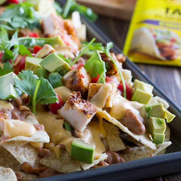 Whether for family dinner or game night, everyone will love these Grilled Chicken Nachos. Tortilla chips are topped with beans, taco seasoned grilled chicken, and an easy homemade cheese sauce in this easy, cheesy Tex-Mex recipe.