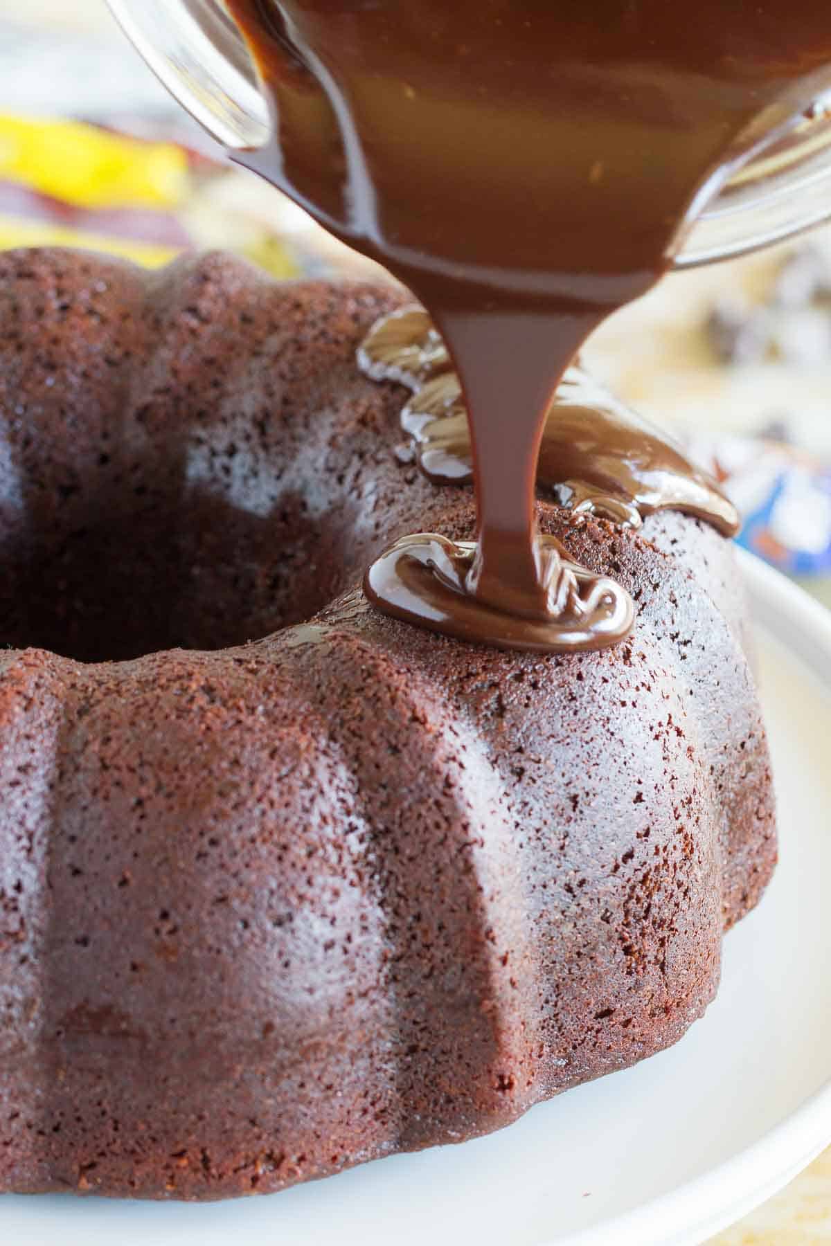 pouring chocolate ganache over a chocolate bundt cake