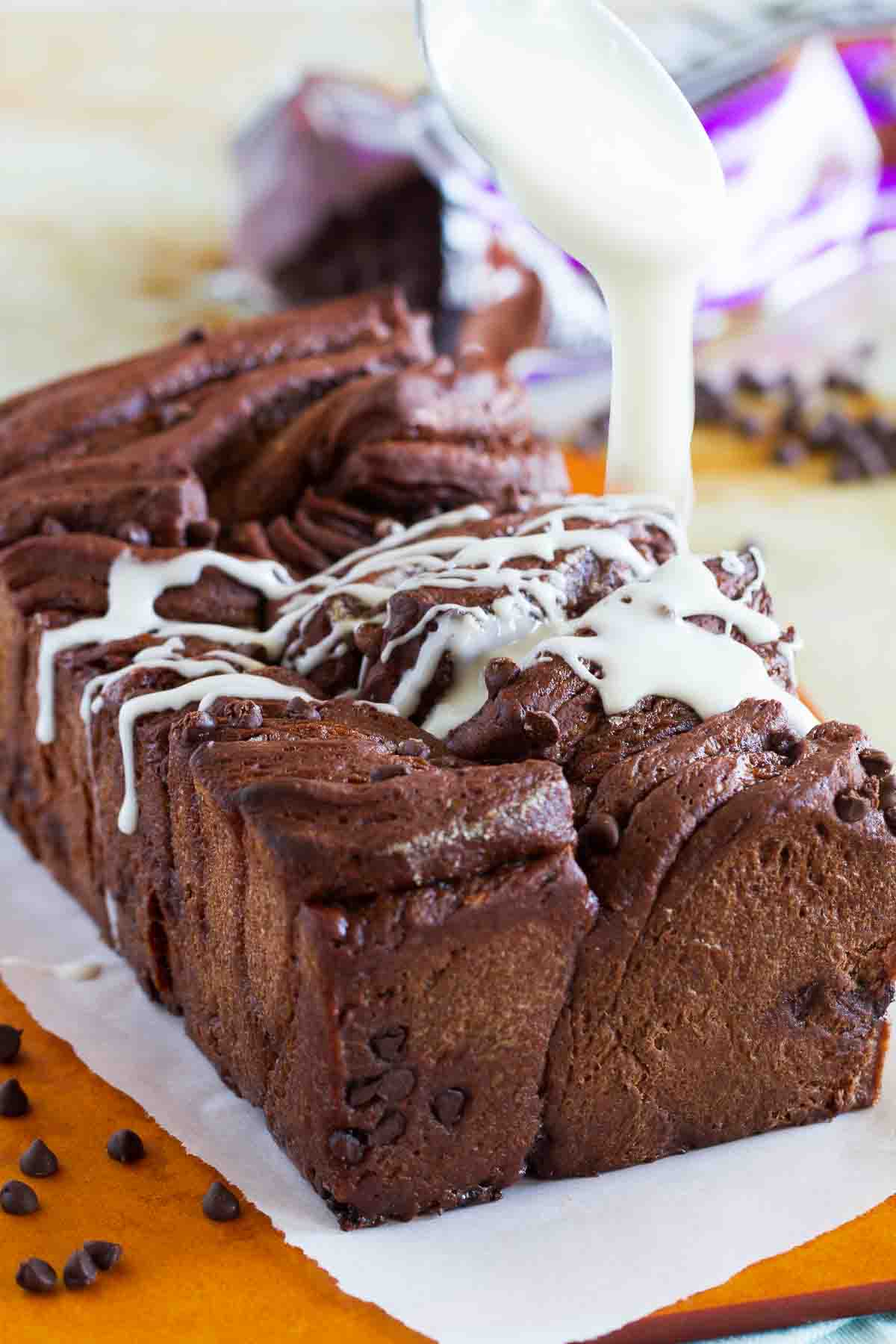 Drizzling icing over chocolate pull apart bread.