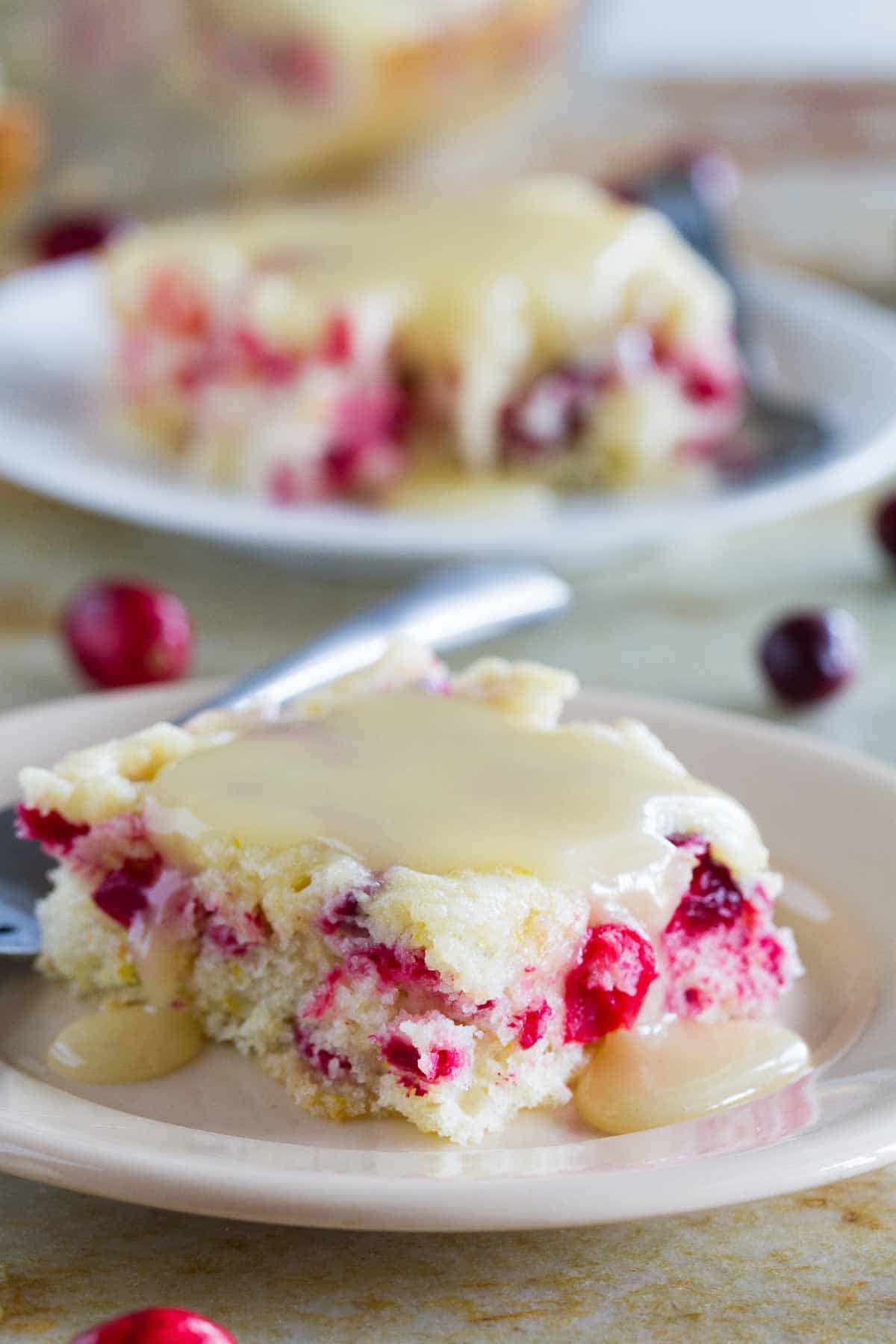 slice of cranberry cake with warm butter sauce on a plate with a fork