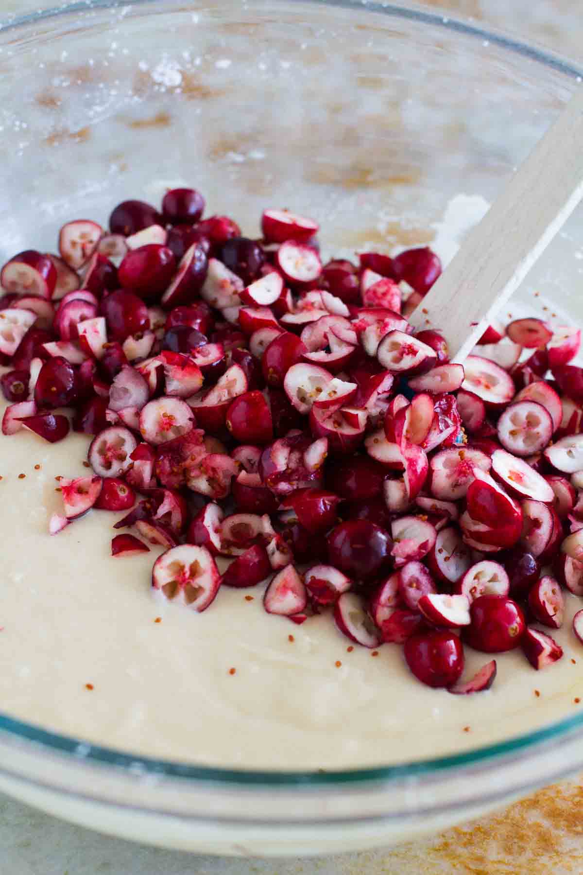 cake batter in a bowl with fresh, chopped cranberries